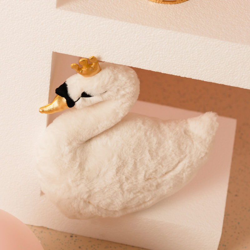 Un joli cygne avec une couronne doré en peluche et sur le gâteau d’anniversaire